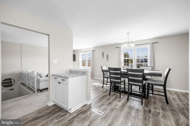 dining room with baseboards, wood finished floors, visible vents, and a chandelier