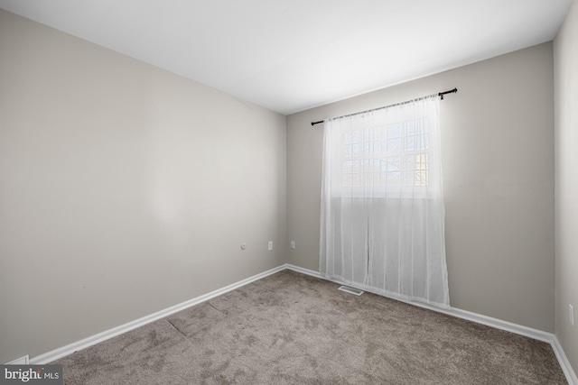 carpeted spare room with visible vents and baseboards