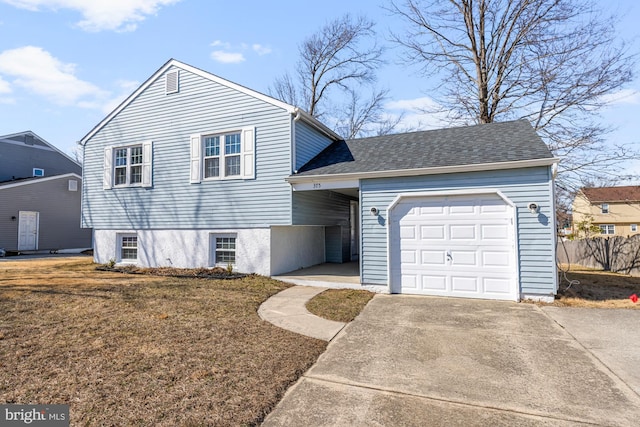 tri-level home with driveway, fence, roof with shingles, a front yard, and an attached garage