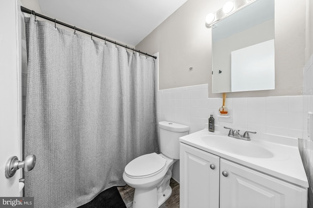 full bathroom with vanity, wood finished floors, a wainscoted wall, tile walls, and toilet