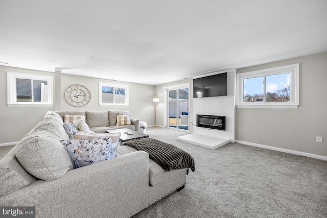 carpeted living room with a healthy amount of sunlight, a fireplace, and baseboards