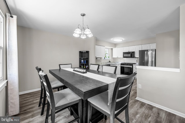 dining space with a notable chandelier, wood finished floors, and baseboards