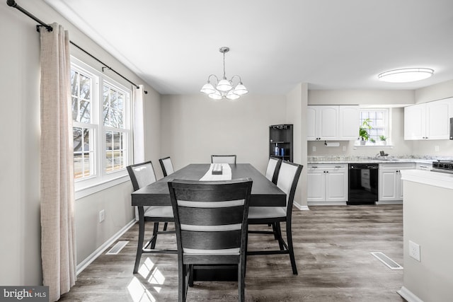 dining space featuring a chandelier, visible vents, baseboards, and wood finished floors