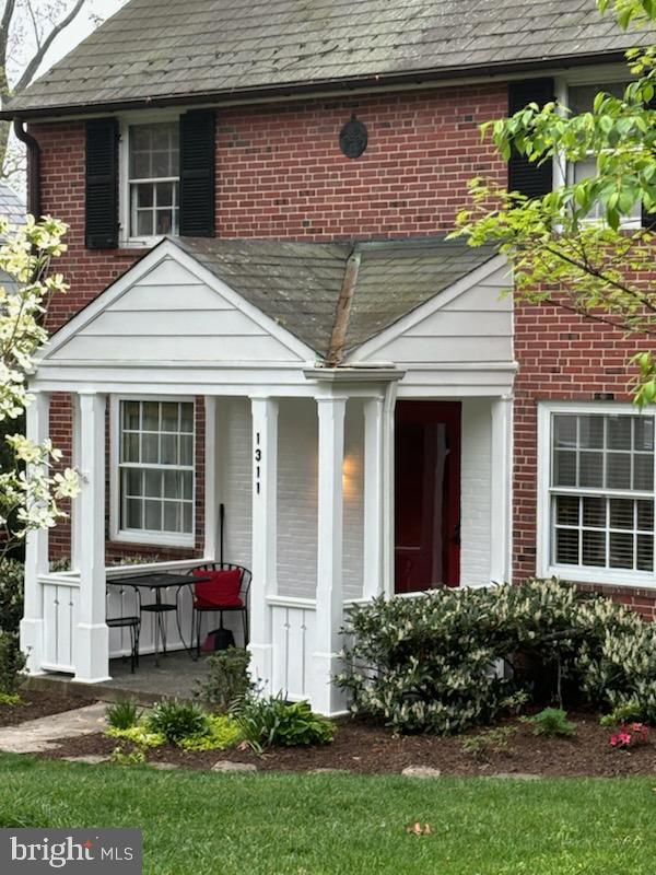 entrance to property featuring covered porch and brick siding