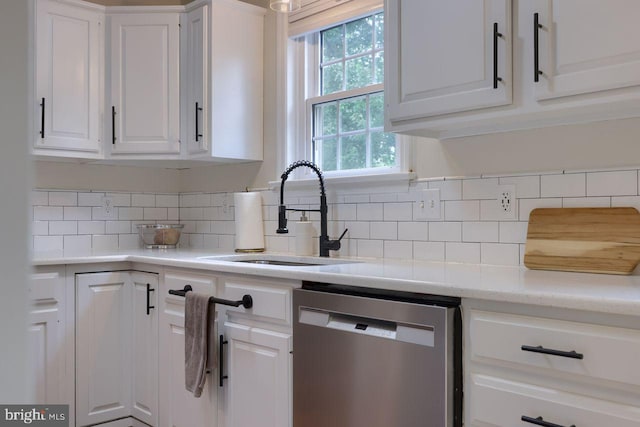 kitchen featuring a sink, decorative backsplash, stainless steel dishwasher, and white cabinetry