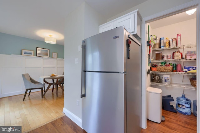 kitchen featuring white cabinets, freestanding refrigerator, and wood finished floors