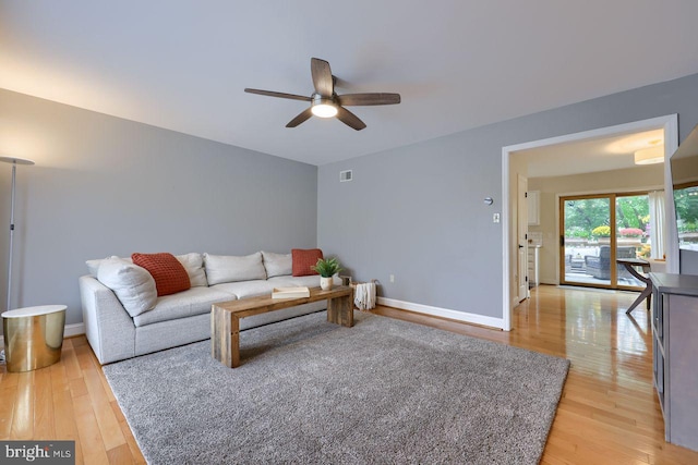 living area featuring visible vents, baseboards, light wood-style floors, and a ceiling fan