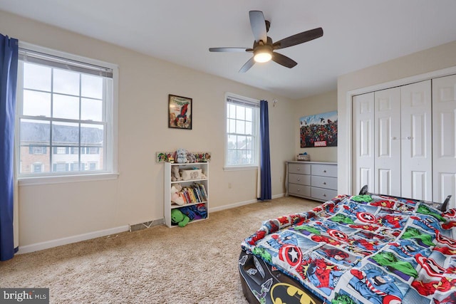 carpeted bedroom featuring a closet, baseboards, and a ceiling fan