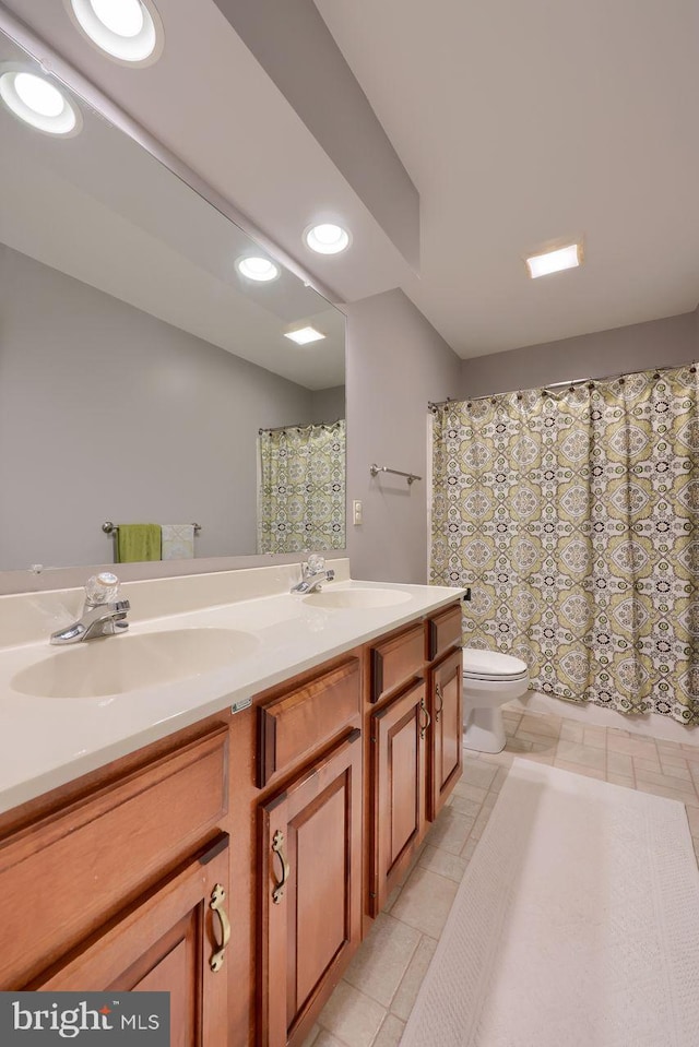 full bathroom featuring double vanity, recessed lighting, toilet, and a sink