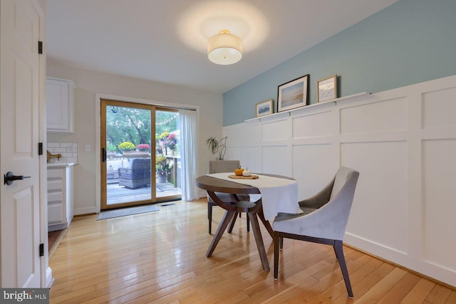 dining area with light wood finished floors and a decorative wall