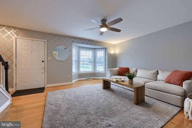 living room featuring visible vents, wallpapered walls, light wood finished floors, baseboards, and ceiling fan