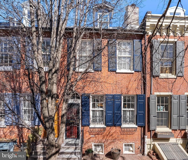 townhome / multi-family property with brick siding and a chimney