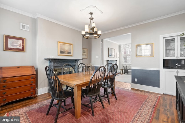 dining space featuring crown molding, a fireplace, visible vents, and dark wood-style flooring