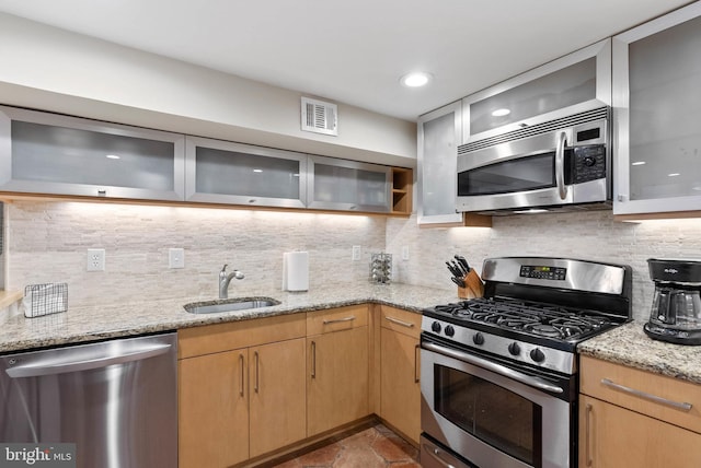 kitchen with light stone counters, visible vents, a sink, appliances with stainless steel finishes, and backsplash