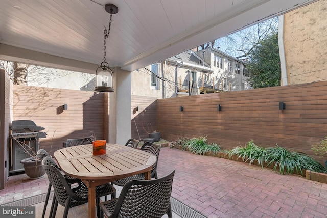 view of patio featuring outdoor dining area, a fenced backyard, and a grill