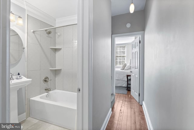 ensuite bathroom with baseboards, shower / washtub combination, ensuite bathroom, wood-type flooring, and crown molding