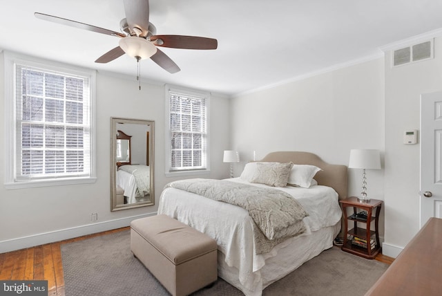 bedroom with visible vents, baseboards, hardwood / wood-style floors, and ornamental molding