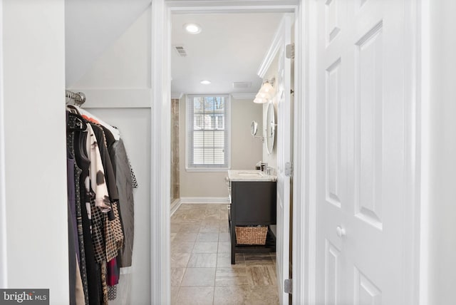 full bathroom with vanity, visible vents, baseboards, a stall shower, and a walk in closet