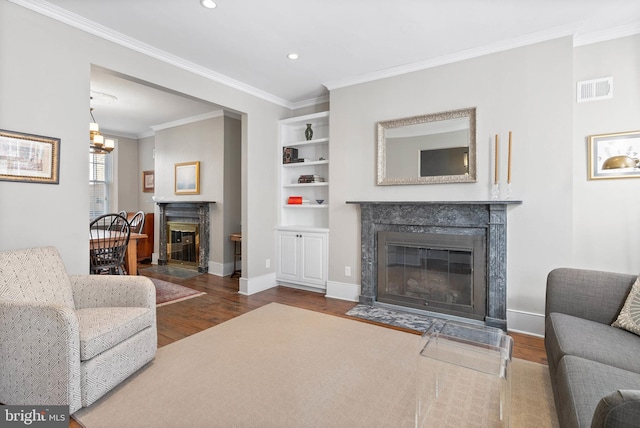 living area featuring wood finished floors, crown molding, a fireplace, and visible vents