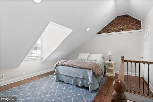 bedroom with visible vents, vaulted ceiling with skylight, wood finished floors, and baseboards