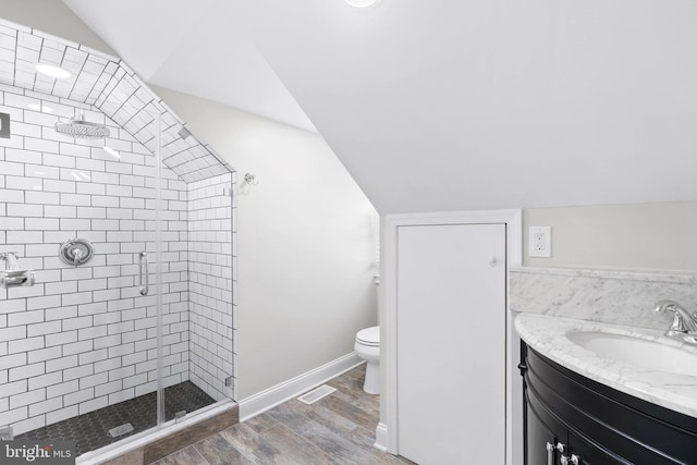 bathroom featuring visible vents, toilet, lofted ceiling, a stall shower, and wood finished floors