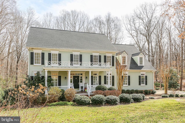 view of front of house with a balcony, covered porch, a front yard, and a shingled roof