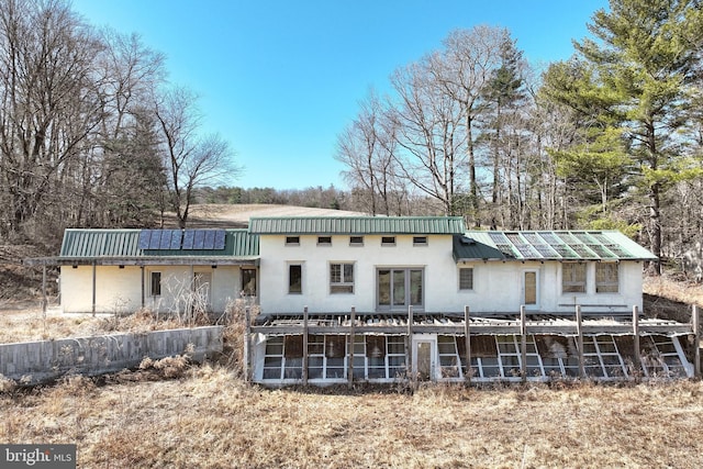 rear view of house featuring solar panels and metal roof