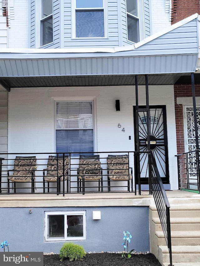 doorway to property featuring brick siding and covered porch