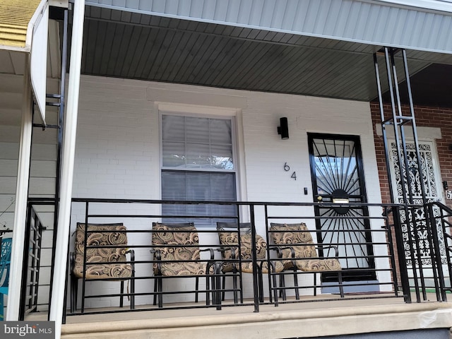 entrance to property featuring brick siding and a porch