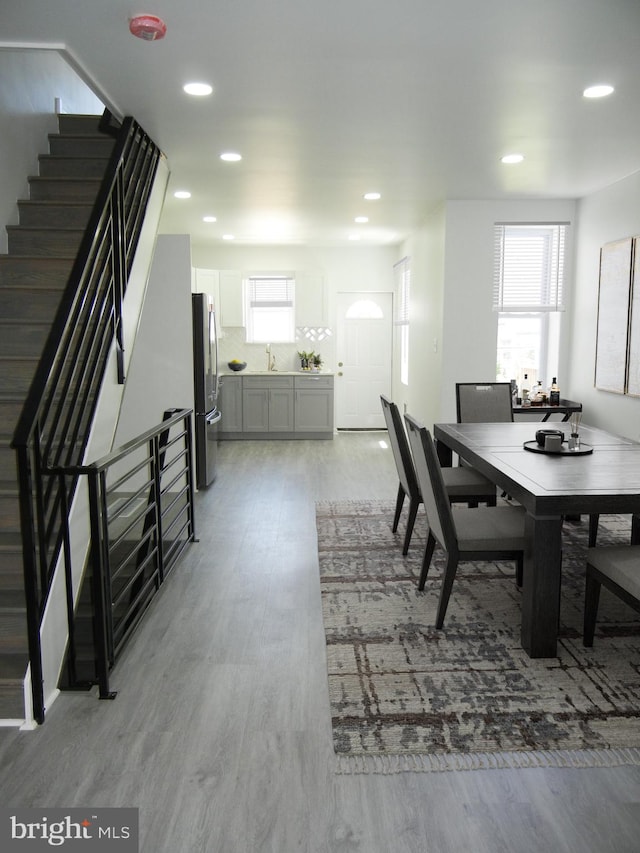 dining area featuring recessed lighting, a healthy amount of sunlight, stairs, and wood finished floors