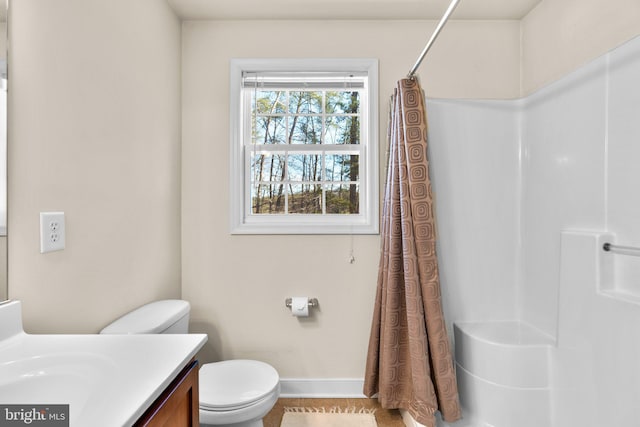 bathroom with toilet, vanity, a shower with shower curtain, and baseboards