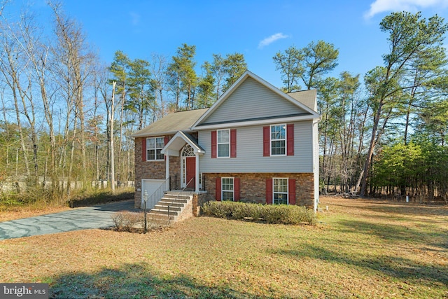 view of front of house featuring a garage, stone siding, a front yard, and driveway