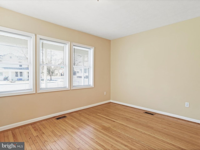 unfurnished room featuring light wood-style floors, visible vents, and baseboards