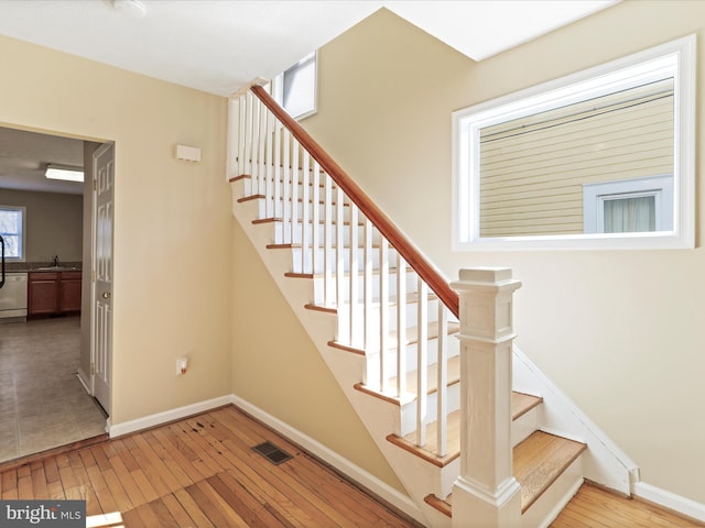 staircase with visible vents, baseboards, and hardwood / wood-style floors