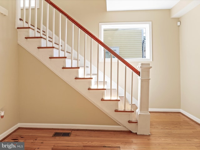 staircase with hardwood / wood-style flooring, baseboards, and visible vents