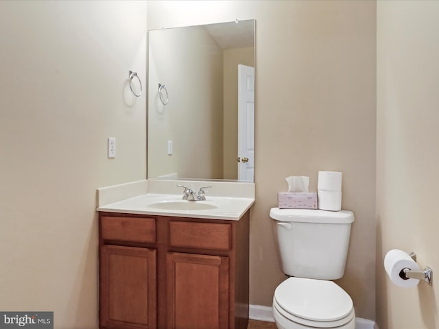 half bath with baseboards, toilet, and vanity