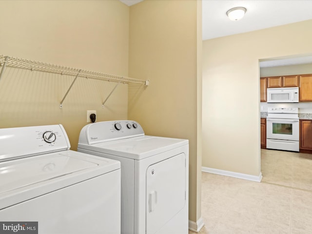 laundry room featuring washer and dryer, baseboards, and light tile patterned floors