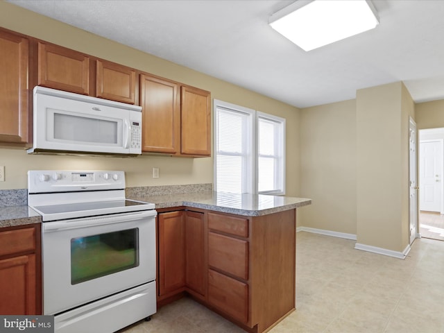 kitchen featuring white appliances, a peninsula, baseboards, and light countertops