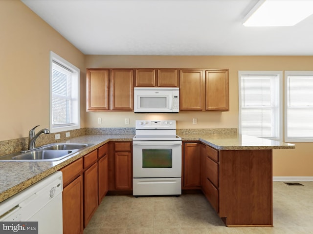 kitchen with white appliances, visible vents, a peninsula, a sink, and brown cabinets