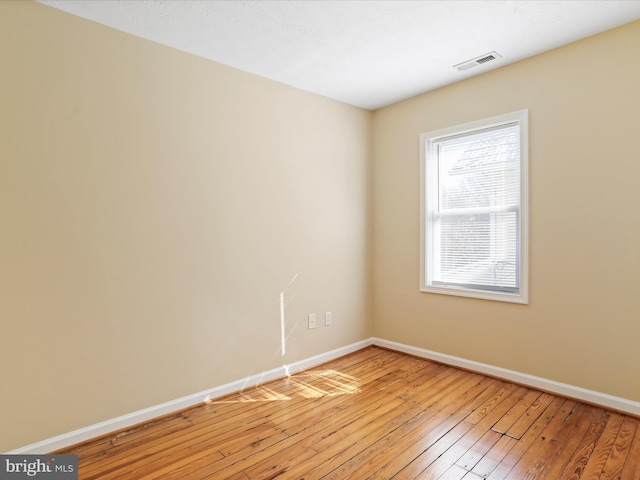 empty room with visible vents, baseboards, and light wood finished floors