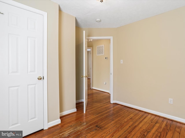 interior space with hardwood / wood-style flooring, visible vents, and baseboards