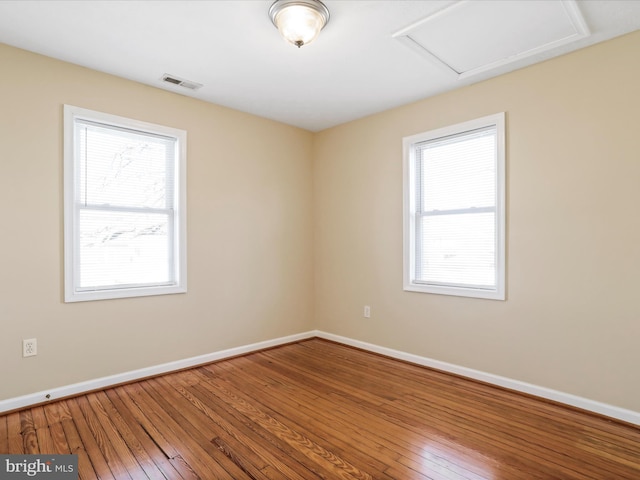 unfurnished room featuring attic access, baseboards, visible vents, and wood-type flooring