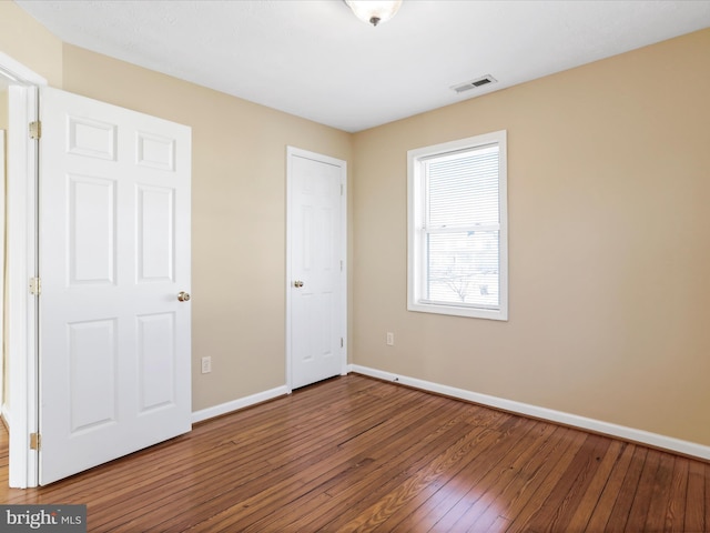 unfurnished bedroom featuring visible vents, baseboards, and hardwood / wood-style floors