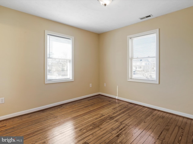 spare room with hardwood / wood-style flooring, baseboards, and visible vents