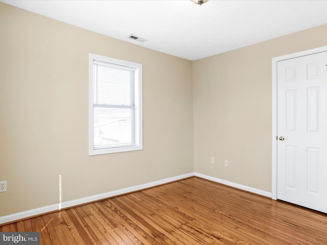 unfurnished room featuring visible vents, light wood-style floors, and baseboards