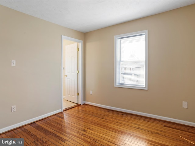 unfurnished room with baseboards and hardwood / wood-style floors