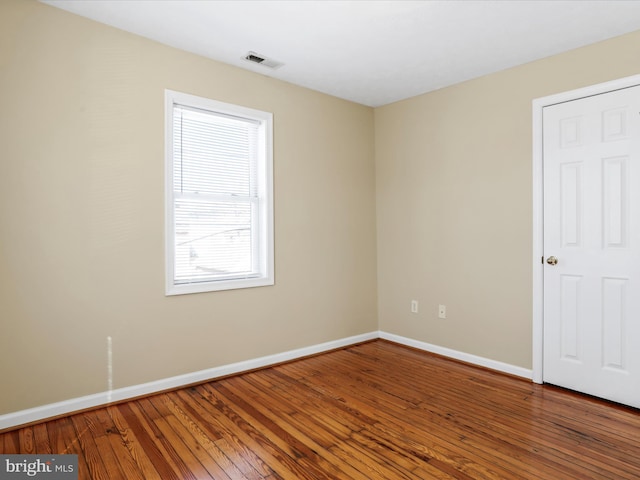 spare room featuring visible vents, baseboards, and hardwood / wood-style flooring