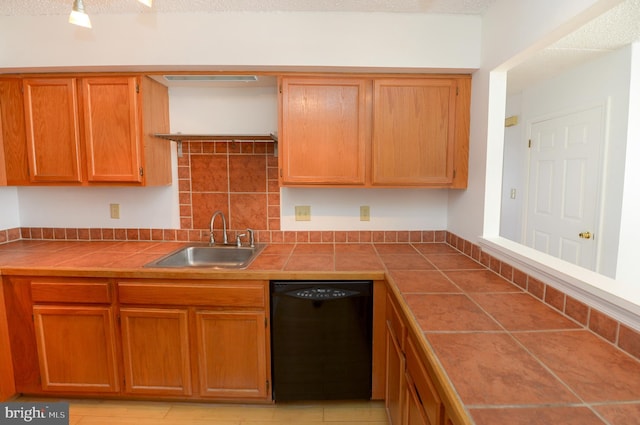 kitchen with tile counters, brown cabinetry, black dishwasher, and a sink