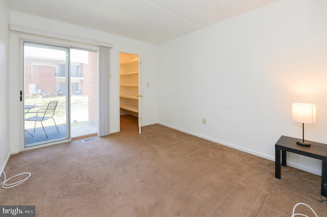 carpeted spare room with visible vents and baseboards