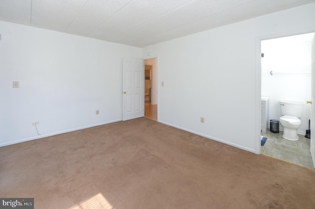 unfurnished bedroom with connected bathroom, baseboards, and carpet flooring